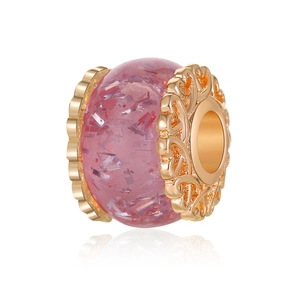 Makroansicht einer rosa Harzperle mit Silberfolie und verzierten goldenen Metallkanten
