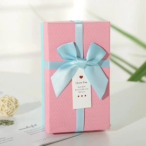 Scatola regalo di Natale rosa con nastro azzurro ed etichetta romantica pendente