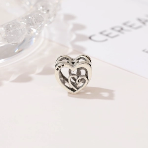 Detalle macro del abalorio de corazón hueco en plata vintage con grabado MOM para pulseras