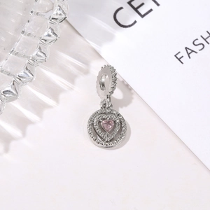 Macro detail of a silver pendant featuring a pink heart stone and pavé setting