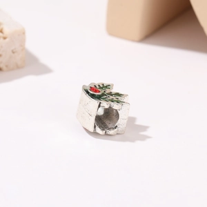 Macro-opname van een zilveren hulstbladbedeltje met rode strass voor kerstsieraden DIY