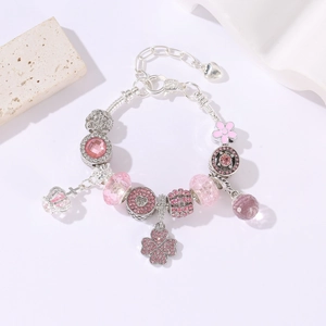 Vista dettagliata del bracciale con ciondoli argento, cristalli rosa, corone e fiori