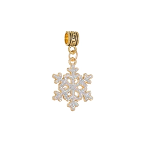 Détail d'un pendentif flocon de neige doré avec paillettes blanches et bélière gravée