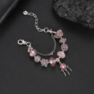 Dettaglio di un bracciale acchiappasogni rosa con ciondoli a farfalla e piume