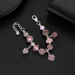 Dettagli di perline in cristallo rosa e ciondoli corona su bracciale d'argento
