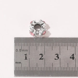 Detailed macro view of 10mm silver bead with pink crystals beside a measuring scale