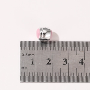 Makroaufnahme einer 10mm rosa Emaille-Perle mit Silberkern neben einem Metalllineal