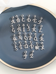 Makroaufnahme von silbernen Buchstaben-Anhängern A-Z mit Strasssteinen für DIY-Schmuck