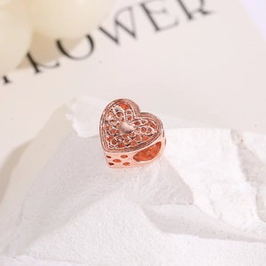 Detalle macro de un abalorio de corazón hueco en oro rosa con patrones de filigrana