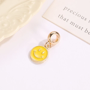 Macro detail of a yellow enamel smiley face charm with gold metal base for DIY jewelry