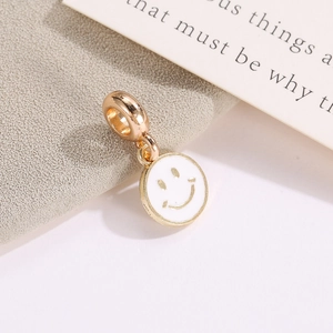 Detailed macro of a golden smiley face enamel pendant with a large ring for DIY jewelry making