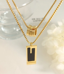 Close-up of gold stainless steel double layer necklace with triple ring and bar pendants