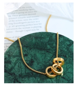 Close-up of golden triple interlocking ring pendant on a box chain for a sleek modern look