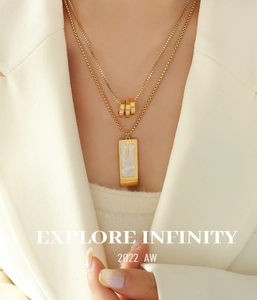 Close-up of double-layered gold necklace with marble pendant and three-ring charms