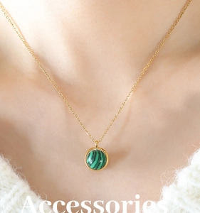 Détail d'un collier en titane doré avec pendentif turquoise rotatif porté par un mannequin