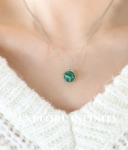 Gros plan du pendentif géométrique en turquoise sur une fine chaîne en acier titane argent
