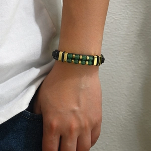 Bracelet en pierre naturelle avec cordon noir et détails dorés porté au poignet