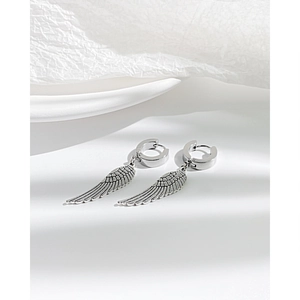 Détail de boucles d'oreilles ailes vintage argentées avec textures de plumes précises