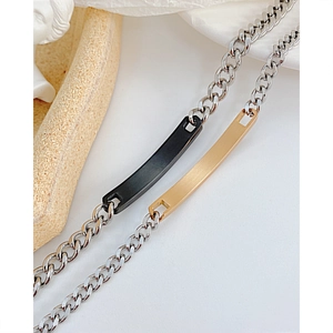 Détail de bracelets de couple avec barres noires et dorées sur chaîne à maillons argent