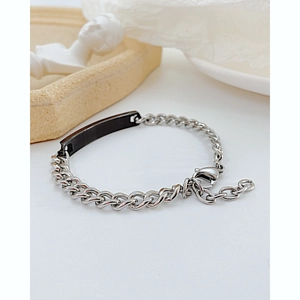 Détail d'un bracelet gourmette argenté avec une plaque rectangulaire noire polie