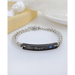 Détail de la plaque gravée Her Beast sur un bracelet gourmette argenté pour couples