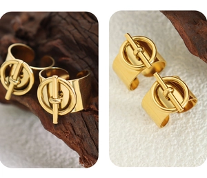 Detalle de dos anillos anchos de acero inoxidable dorado con cierre OT en madera
