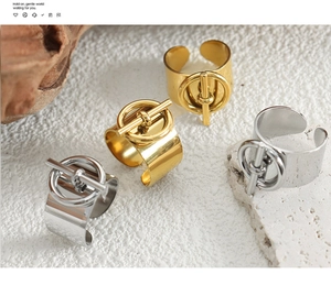Anillos abiertos dorados y plateados con cierre OT sobre superficie de piedra
