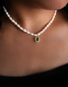 Dettaglio della collana di perle barocche con pendente smeraldo verde e cornice oro