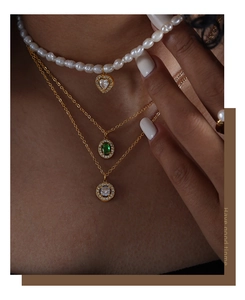 Dettaglio ravvicinato di una collana a tre strati in oro con perle e cuore
