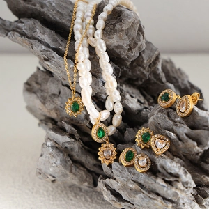 Set collana di perle d'acqua dolce e orecchini di smeraldo su sfondo di roccia naturale