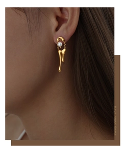 Detailed view of gold melting drop earrings with white pearl and hanging chain on model