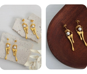 Detail view of gold lava drop earrings with white pearls on a textured background
