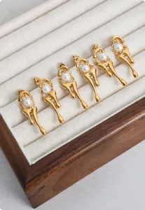 Detail view of gold molten liquid drop earrings with white pearls in a jewelry box