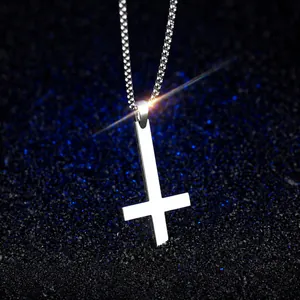 Macro shot of minimalist inverted cross pendant in polished steel on starry blue surface