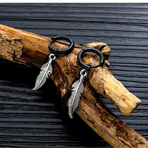 Vista de detalle de pendientes de aro negros con colgantes de pluma en madera seca