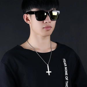 Detail of a polished stainless steel inverted cross pendant on a male model wearing black