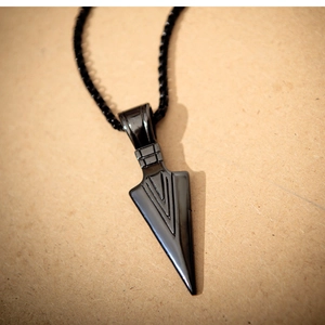 Macro shot of a sleek black arrowhead pendant necklace with a matching bead chain