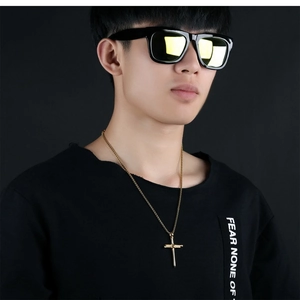 Close-up of a gold cross pendant necklace on a model with stylish gold sunglasses
