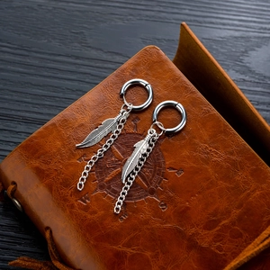 Punk style stainless steel feather tassel chain earrings on vintage leather notebook