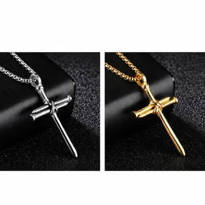 Close-up of hip hop style cross pendant featuring three entwined metallic nails in silver and gold