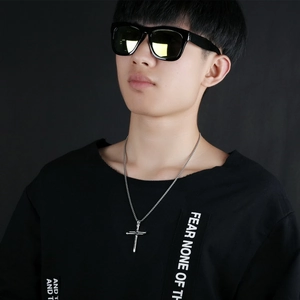 Men's silver cross pendant necklace shown on model against a dark background