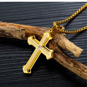 Macro shot of gold-layered cross pendant with carbon fiber inlay on a wooden display