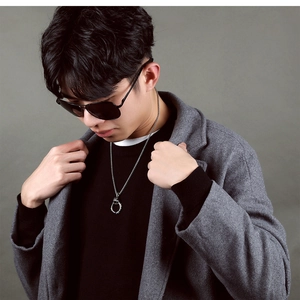 Close-up of men's silver stainless steel necklace with round ring pendant on a gray coat