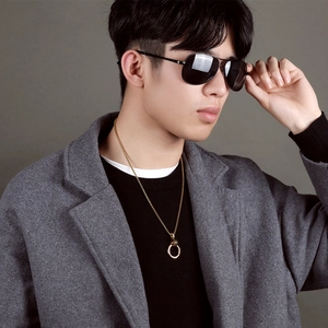 Detail of a men's gold ring pendant necklace with grey wool coat and sunglasses