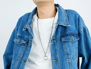 Close-up of a silver retro cross ring pendant necklace worn on a blue denim jacket