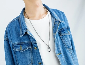 Detail of a vintage steel ring pendant necklace worn over a denim jacket