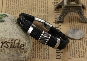 Detalle de una pulsera de cuero negro trenzado de doble capa con cuentas de metal plateado