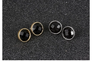 Macro view of round faceted black stone earrings in gold and silver steel bases