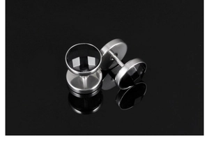 Macro shot of stainless steel stud earrings with black inlay on a reflective surface