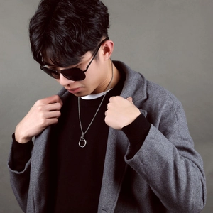 Hip hop style titanium steel cross necklace for men on a grey wool coat background